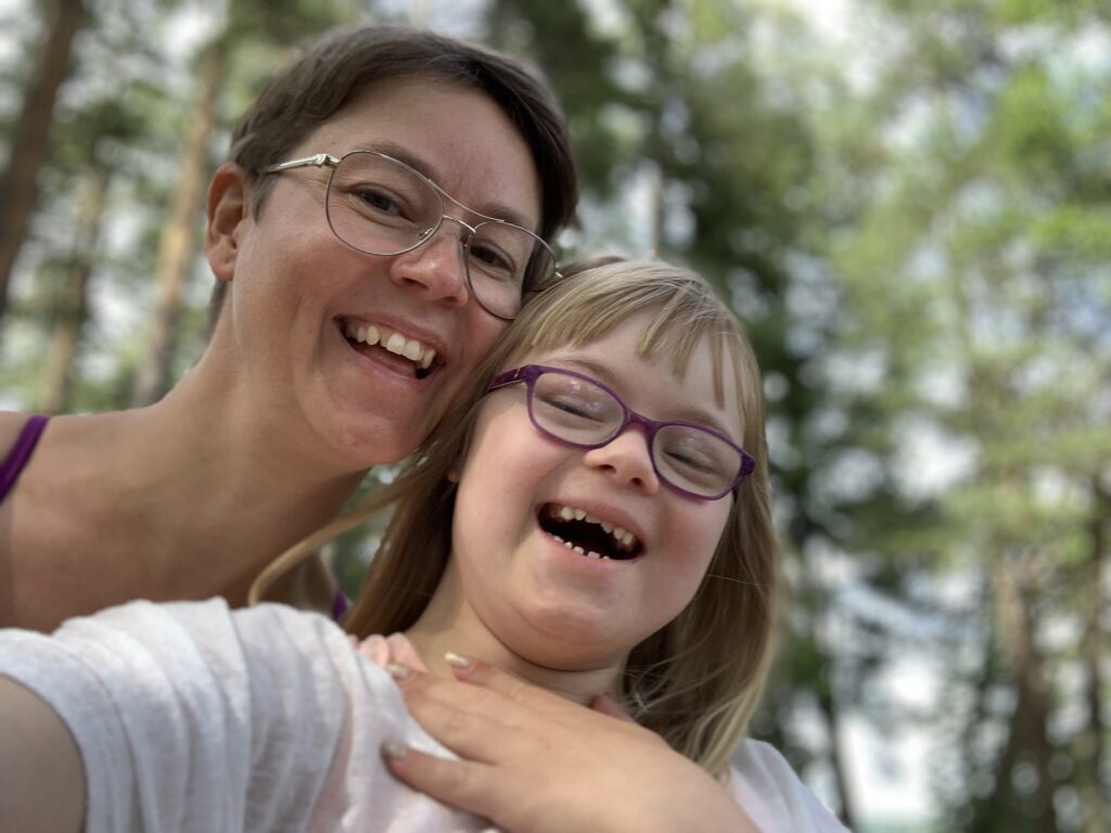 Porträtt av en mor och dotter som skrattar. Dottern har Downs syndrom